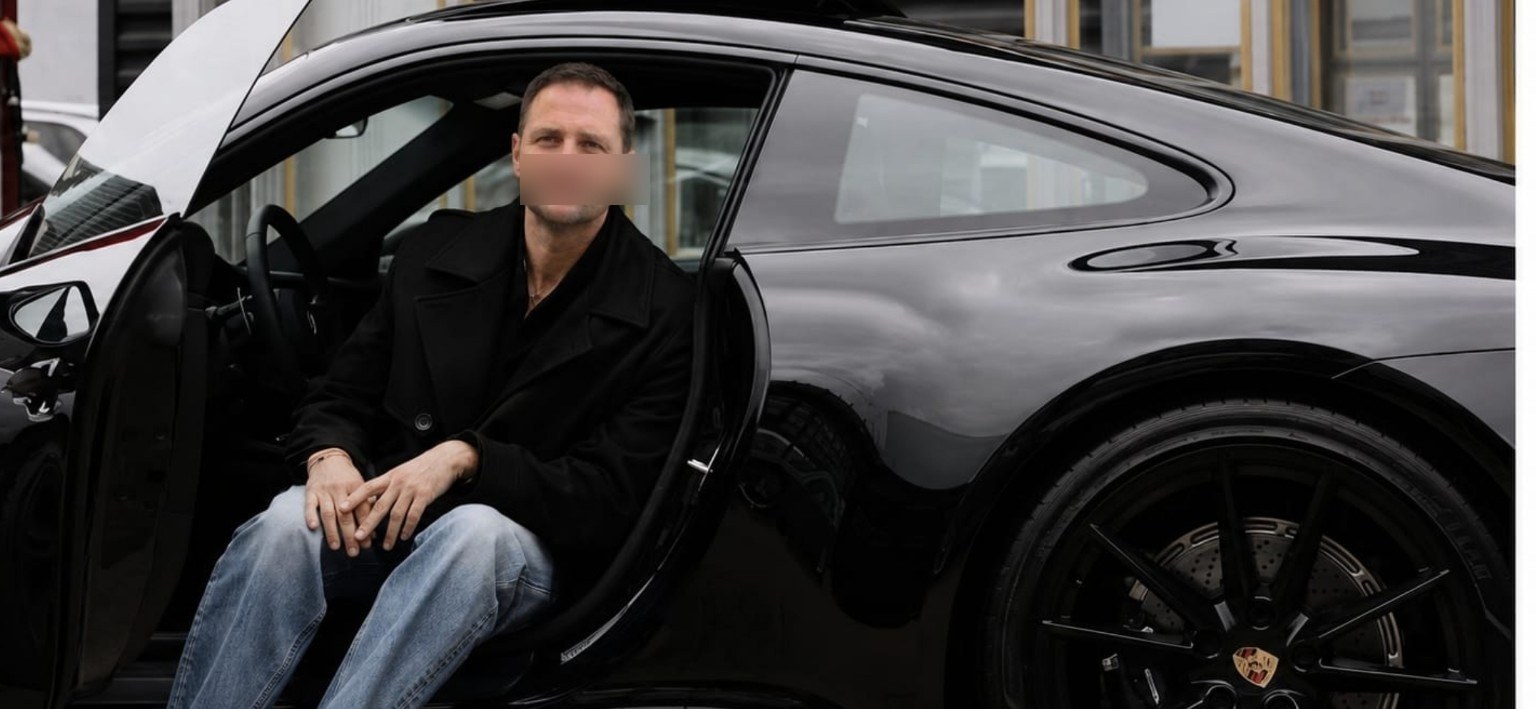 Glenn stapt uit een zwarte Porsche